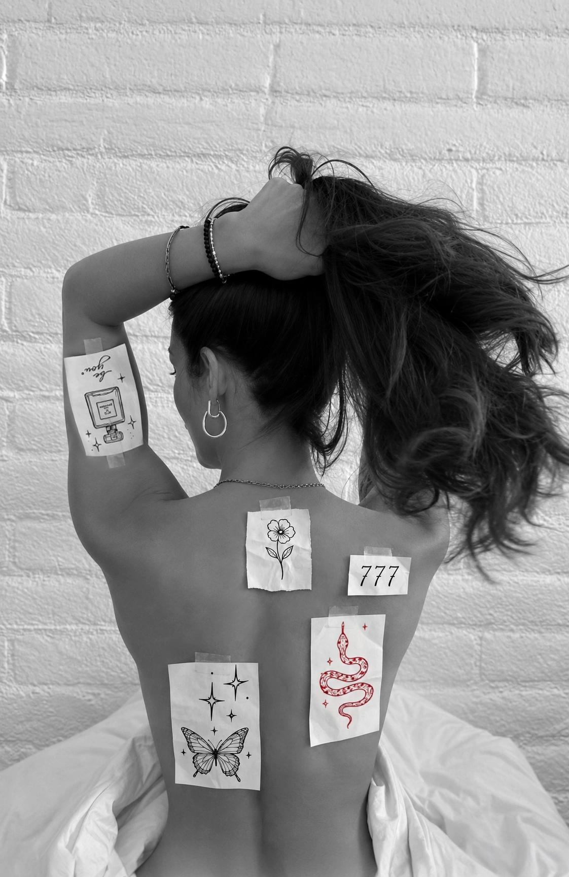 Person testing several paper tattoo placements across their back and arm